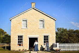 Two Pioneer Women Entering Stone Building