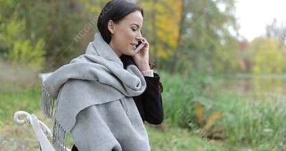 Pretty woman speaking on phone in park