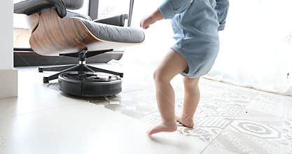 Little boy and robot vacuum cleaner on the floor
