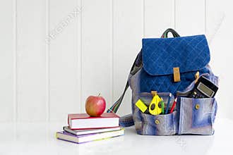 Back to school. Apple, pile of books and backpack on the desk at the school.