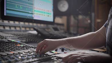 Talanted dj is creating music in a recording studio on a mixing console.