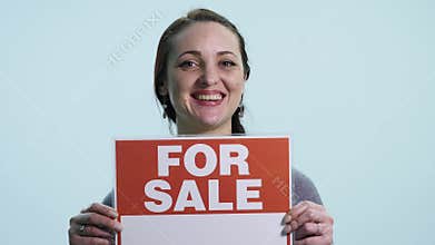 Smiling woman holding white sign board for sale