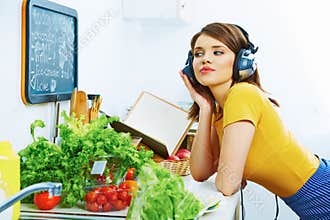 Woman in kitchen cooking with listening music