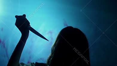 Bloody dark-haired murderer stabbing victim with knife, darkness and horror