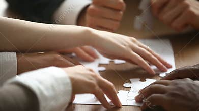 Hands assembling jigsaw puzzle, help support in teamwork concept, closeup