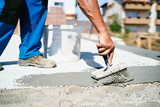 Construction worker using brush and primer for waterproofing house using hydroinsulation materials