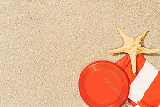 top view of sea star, red frisbee and towel