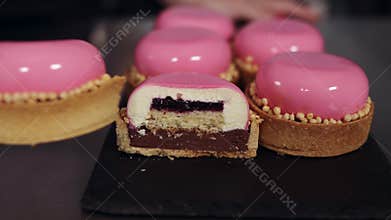 Extremely close up footage. The confectioner shows the finished dessert in a cut, layers. Pink glaze, modern desserts