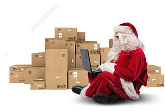 Technological Santa Claus sitting with laptop buys Christmas gifts with e-commerce