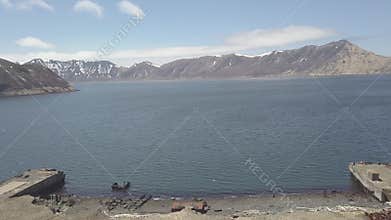 Piers on seashore in background of sea water and mountain landscape drone view