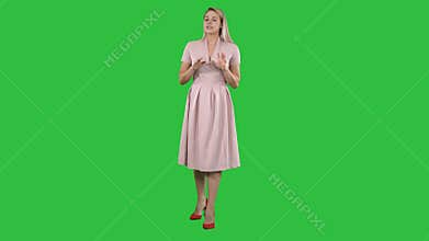 Cute girl full length in pink dress talking to camera and smiling on a Green Screen, Chroma Key.