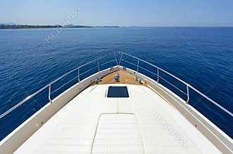 Bow of a luxury motor yacht cruising the blue sea.