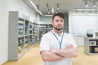 Consultant poses to the camera on the background of a light electronics store