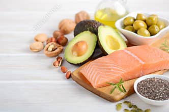 Selection of healthy unsaturated fats, omega 3 - fish, avocado, olives, nuts and seeds.