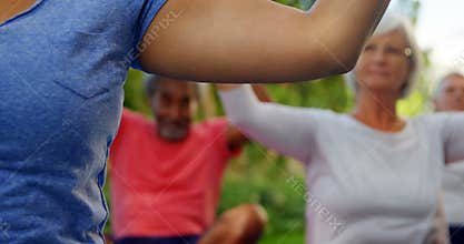 Trainer and seniors performing yoga in garden 4k