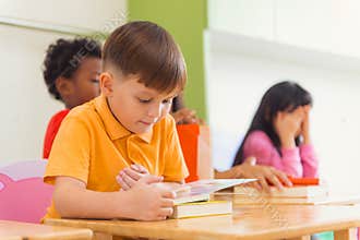 Row of multiethnic elementary students reading book in classroom. Vintage effect style pictures