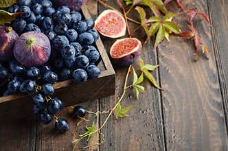 Fresh Black Grapes and Figs in Dark Wooden Tray on Wooden Table