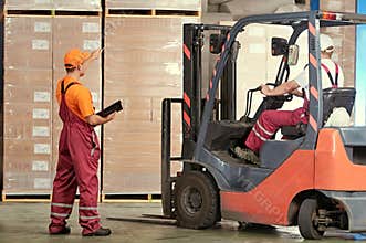 Warehousing and storage. warehouse workers works with forklift loader