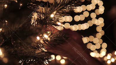 Woman decorating the lights on a Christmas tree with bokeh lights background