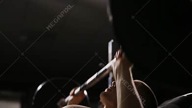 Inflated strong man with big muscles raises the bar lying on the bench close up.