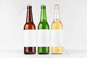 Three beer bottles longneck 500ml different colors with blank white label on white wooden board, mock up.
