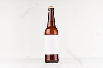 Brown longneck beer bottle 500ml with blank white label on white wooden board, mock up.