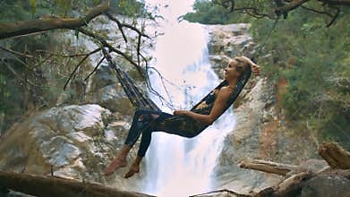 Girl Lies on Hammock against Pictorial Waterfall