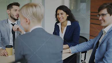 Business team chatting while sitting in modern office indoors during coffee break
