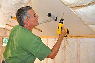 Man installing drywall on ceiling