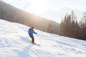 Skier in sunset mountains, downhill skiing