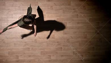 Silhouette of young girl is dancing with hands on wooden floor, ballet concept, movement concept, top shot