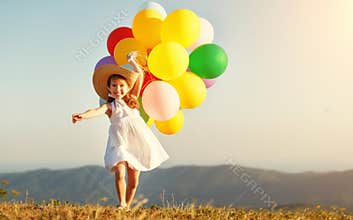 Happy child with balloons at sunset in summer