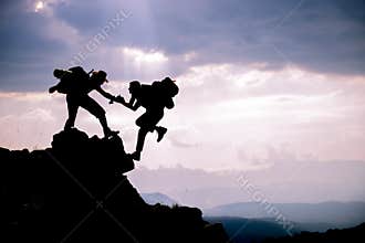 Silhouette of helping hand between two climber.Adventurous people;Hikers climbing on mountain. Help, risk, support, assistance