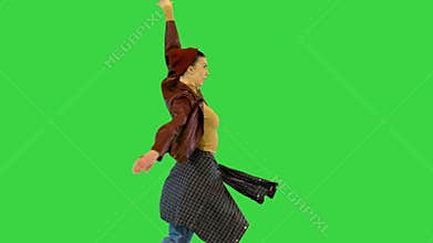 Young girl in urban dance clothes makes a turn and runs away on a Green Screen, Chroma Key.