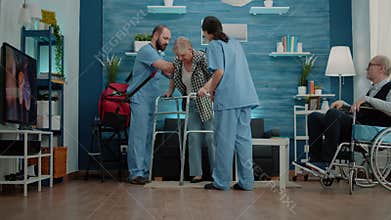 Nurses helping disabled pensioner to use walk frame