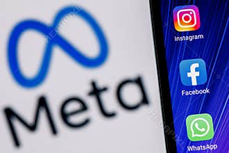Facebook changes its name to Meta. Smartphone with Facebook, Whatsapp and Instagram app icon on the background of Meta logo