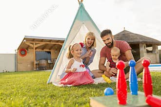 Parents playing bowling with their children while camping in the backyard