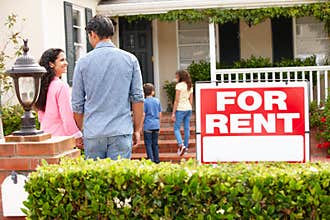 Hispanic family standing outside home for rent