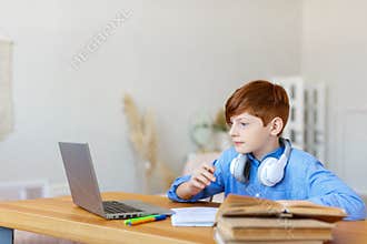 Teen boy doing homework online at home. He closely follows the teacher's story online.