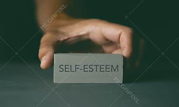 Man showing a toy block with the text self-esteem