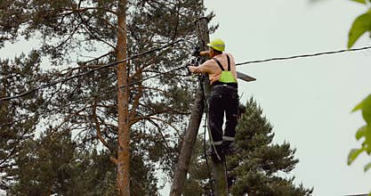 Electrical lineman connecting wires on electric pole. powerline maintenance and repair