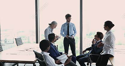 Diverse employees discuss agenda during morning briefing in office