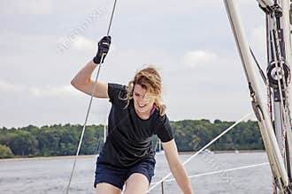 Woman holding ropes walking across deck of sailboat