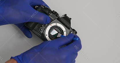 Cleaning digital mirrorless camera sensor with swab from dust and dirt.