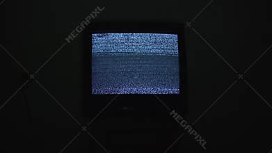 Broken tv screen with noise analog static signal in black room at night