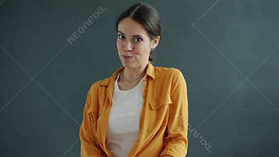 Slow motion of shy and romantic girl waving hand and winking flirting on gray background