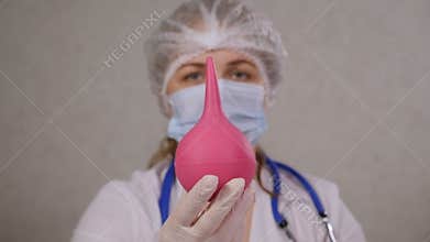 Close-up portrait of a doctor or nurse holding an enema in a hospital.
