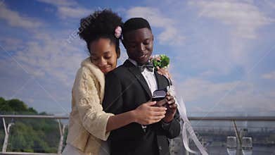 Happy wealthy African American bride and groom admiring wedding rings smiling hugging. Confident rich couple getting