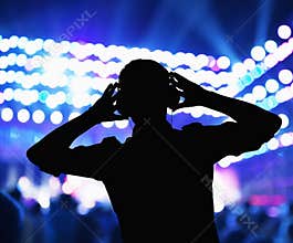 Silhouette of DJ wearing headphones and performing at a night club