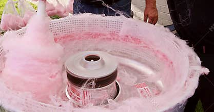 Delicious treat is prepared outdoors using a machine pan for making pink cotton candy